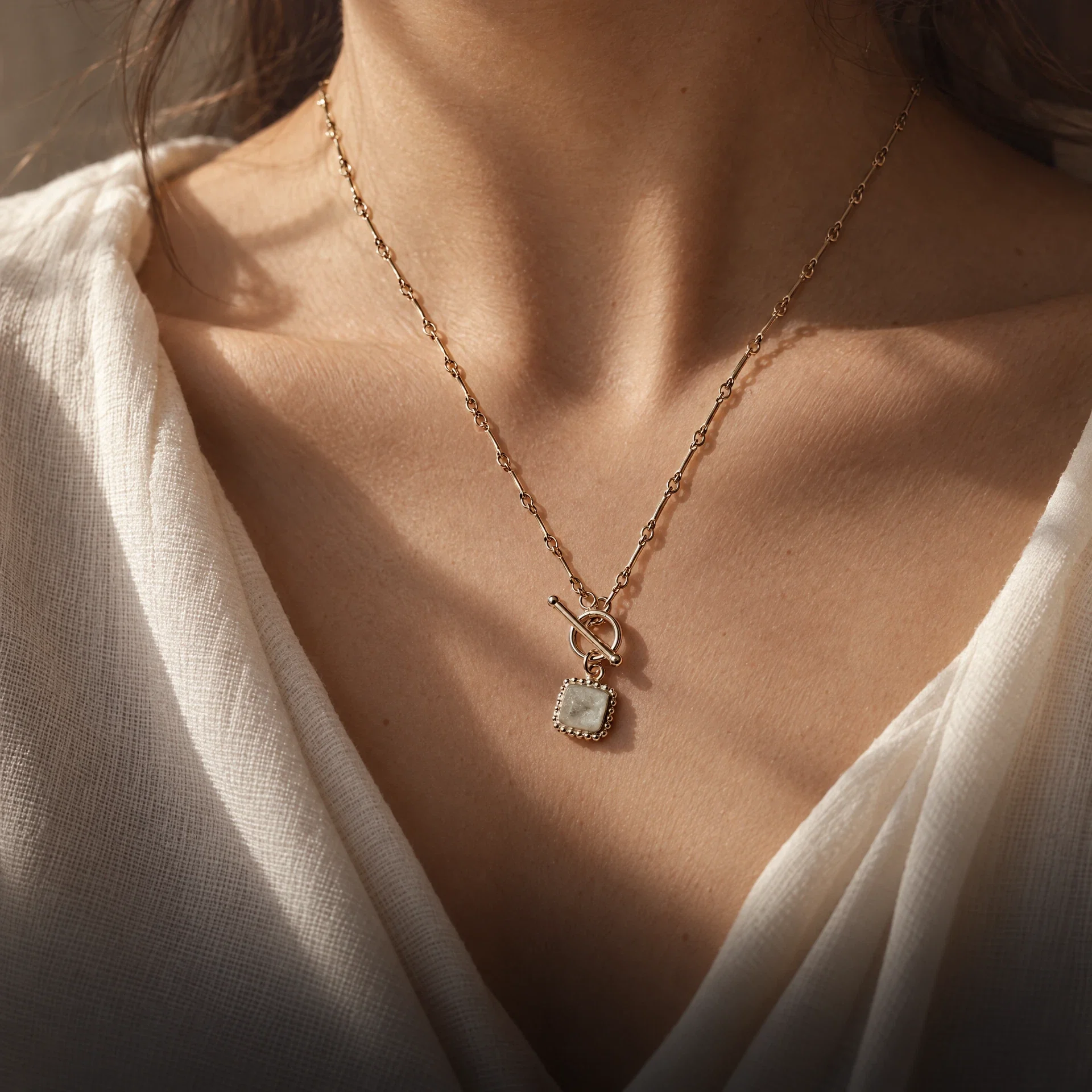 Pale keepsake pendant styled against an ivory neckline